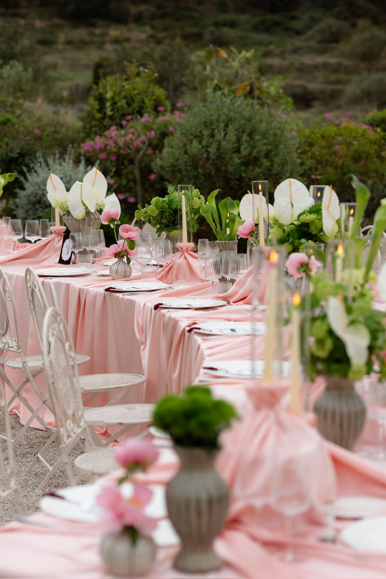 Mesa larga de banquete con mantelería rosa y flores