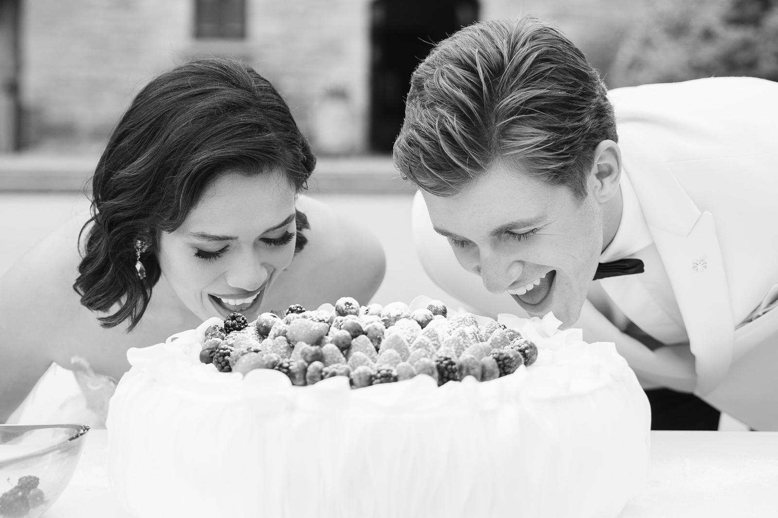 Pareja de novios sonriendo frente a su tarta de boda
