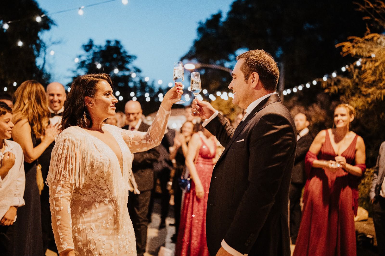 Pareja brindando con sus invitados al anochecer