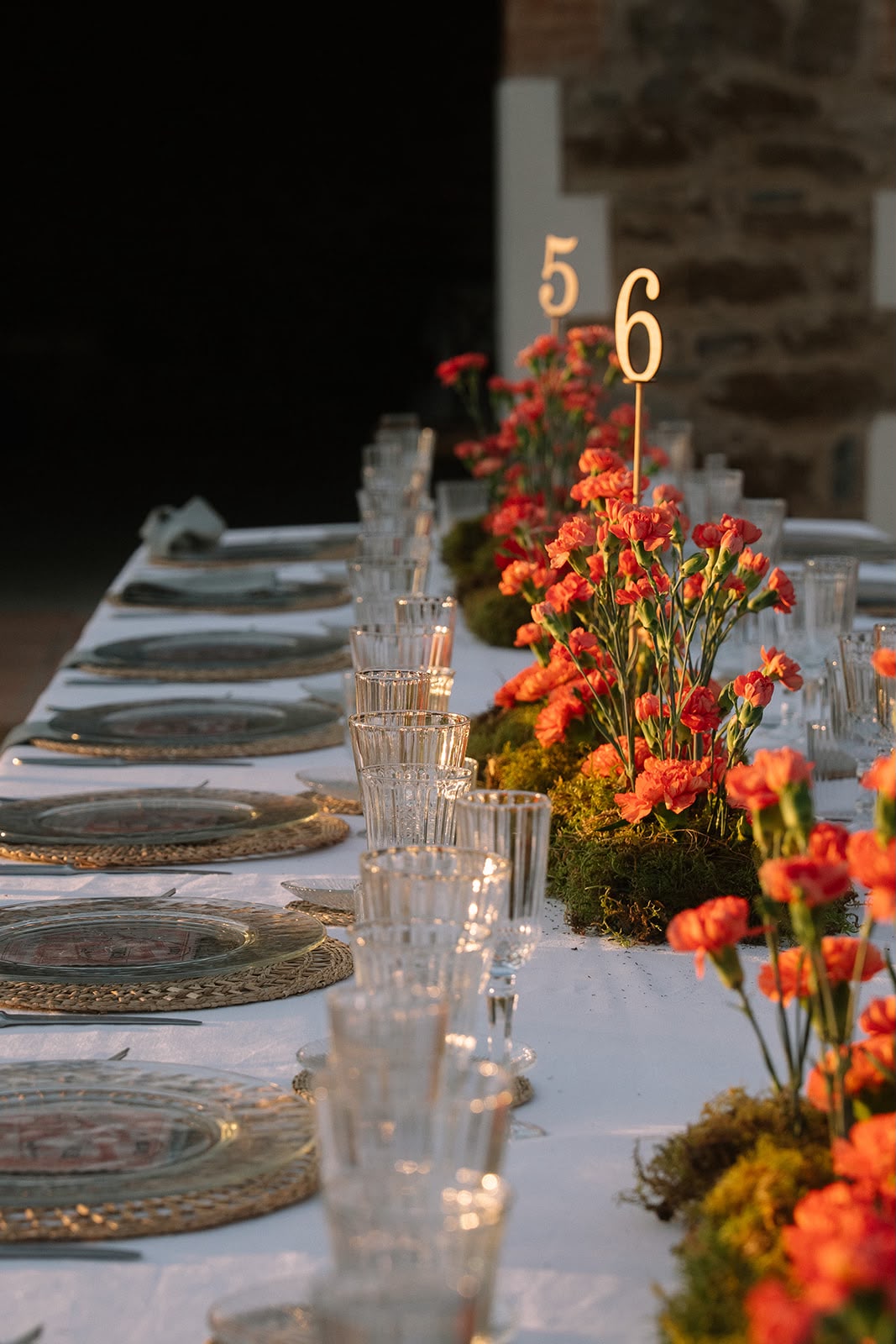 Mesa de boda decorada con flores naranjas y números de mesa