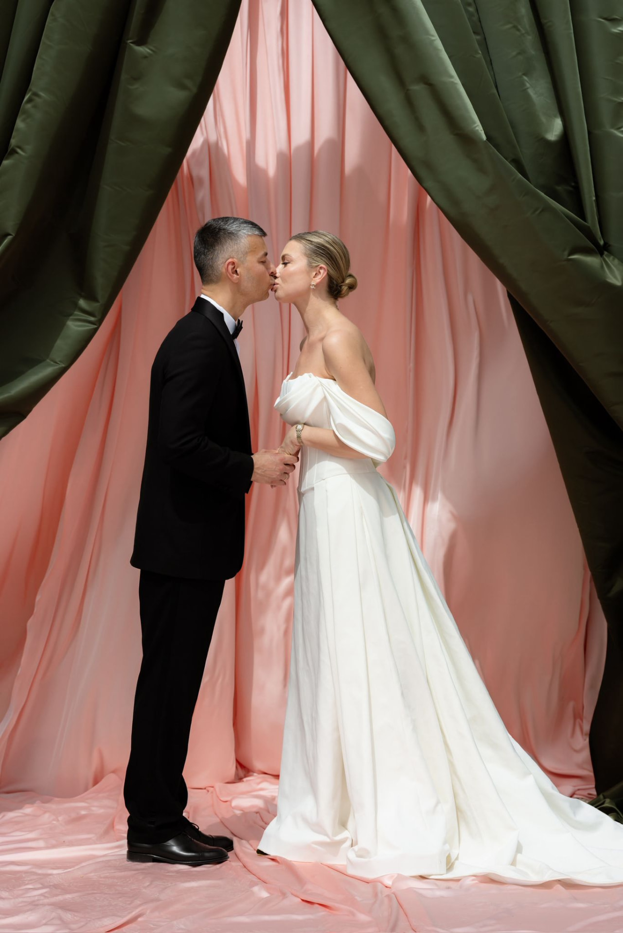 Novios en un photocall de telas rosas y verdes