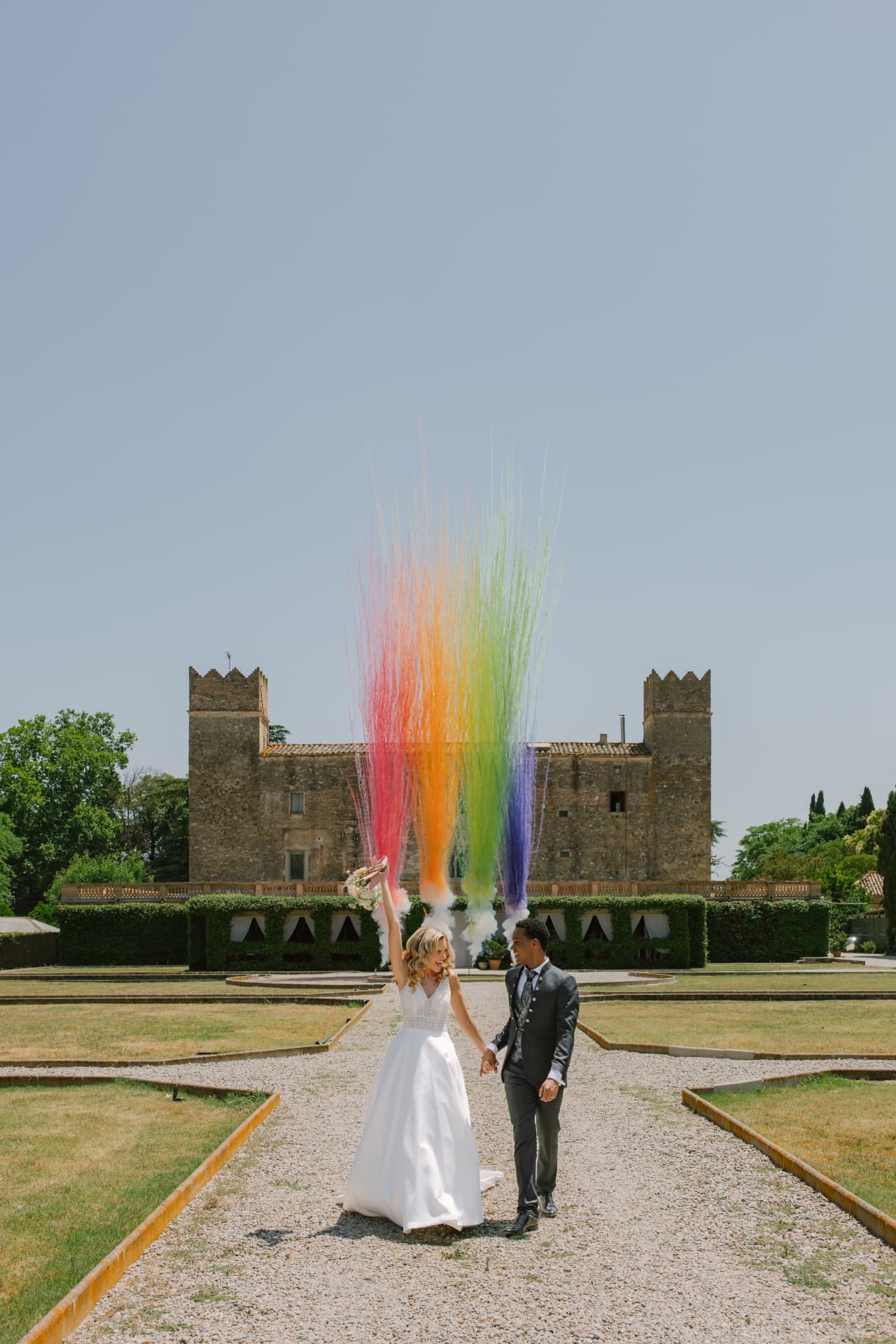 Pareja celebrando con confeti de colores delante de un castillo