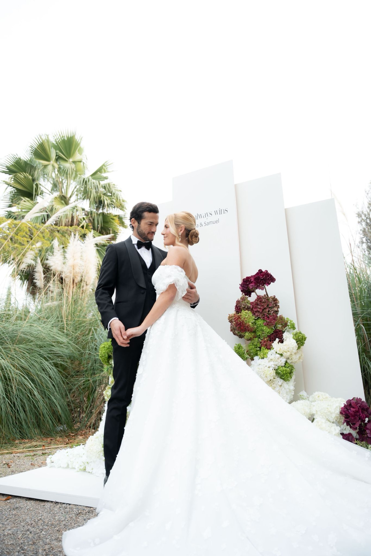 Novios junto a un backdrop floral blanco y burdeos